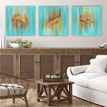 Three turquoise minimalist paintings on the wall, over wooden cadenza, in boho living room. The paintings feature sea shells in gold, copper and yellow shades, and turquoise teal background, inspired by the Maldivian - Caribbean turquoise waters.