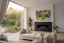 A modern living room with a cream chaise lounge, fireplace, and a colorful abstract wall art piece above the fire. Large windows offer a view of a lush green garden.