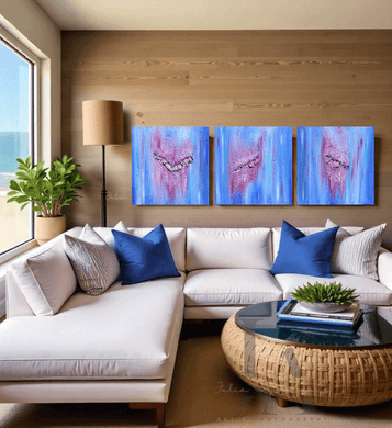 Living room with a large white sectional sofa, blue pillows, and a round coffee table, three blue pink minimalist paintings on the wall, and a large window with an ocean view. The paintings feature jewelry and 3d textures