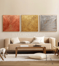Living room with a beige sofa, wooden coffee table, and abstract art triptych on the wall with gold silver and copper colours.