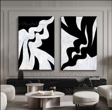 Two abstract black and white artworks on a wall in a modern living room.