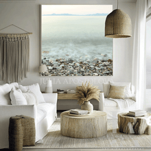 Modern living room with a large beach scene painting, white sofa, and wooden coffee table.