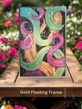 A modern abstract botanical painting with gold floating frame, featuring bold various colors including fuchsia pink, gold, sage-turquoise, and black, with splash gold over, displayed on wooden table surrounded with fuchsia pink and white spring flowers.
