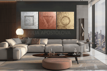 Modern living room with a gray sectional sofa, round coffee table, a city view, and large wall art set of 3 paintings in gold, silver, and copper.