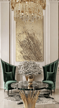 A large gold sculptured original wall painting, with intricate patterns, 3d unique relief textures, gold color scheme, displayed prominently in a luxurious livingroom interior with marble coffee table, modern walls and gold chandelier.