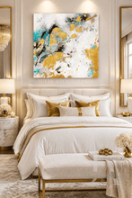 An abstract canvas wall art painting featuring gold leaf, teal blue, black, and white paint strokes, displayed in a modern, elegant bedroom above a neatly made bed with white linens and gold accent pillows.
