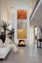 Woman sitting on a white couch in a modern living room with a fireplace and original gold copper silver 3d wall paining by Julia Apostolova.