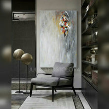 A modern interior space featuring a large abstract minimalist painting with soft gray silver hues, and some gold , white , copper rich textures, Hand-painted by artist Julia Apostolova.