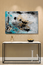 Abstract painting with gold leaf, gray teal, and black, by Julia Apostolova, on a wall above a console table with decorative items.