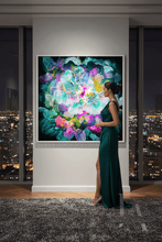 A woman in a dark green evening gown stands beside a large framed abstract floral painting in a modern room with city skyline views at night.