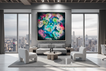A large framed abstract floral painting with vibrant pink, blue, green, and yellow tones hangs on a gray wall in a modern living room with a sofa, two white armchairs, a round coffee table, and large windows overlooking a city skyline.