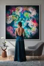 A woman stands with her back to the camera in a modern living room, facing a large framed abstract painting with vibrant splashes of blue, pink, purple, green, teal, white and black. She is wearing a dark teal backless gown.