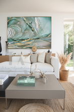 Living room with a large sage green abstract painting above a white sofa.