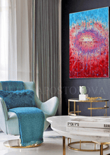 A large abstract painting with a vivid red and blue circular composition hangs on a gray wall above in a modern living room setting with white, blue and gold accents.