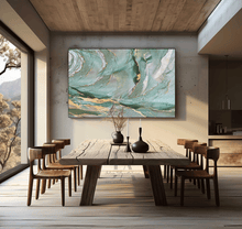Dining room with a large abstract painting on the wall above a wooden table. The painting features sage green, gold, teal colors and shining gold leaf embellishments, by artist Julia Apostolova