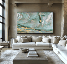 Modern living room with a large abstract painting on the wall above a sofa. The painting features sage green, gold, teal colors and shining gold leaf embellishments, by artist Julia Apostolova