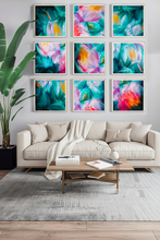 A modern living room featuring a 3x3 grid of nine framed abstract paintings with vibrant teal, pink, yellow, and orange brushstrokes. The paintings are displayed on a light gray wall above a beige sofa with a white throw blanket, a wooden coffee table, and a gray rug, with a large green plant on the left.