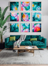 A modern living room featuring a 3x3 grid of nine framed abstract paintings with vibrant teal, pink, orange, and yellow brushstrokes. The paintings are displayed on a light gray wall above a plush emerald green velvet sofa with decorative pillows and a wooden coffee table in front.