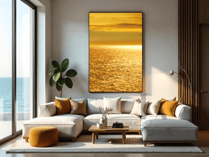 Modern living room with a shimmering golden waters abstract seascape sunset painting on large canvas, hanging over gray sectional sofa. The room feature natural light from a floor-to ceiling windows with an ocean view, puff and a plant.
