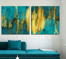 Two abstract paintings with gold and teal hues on a wall above a teal sofa.