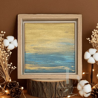 Framed abstract artwork on a wooden stump with decorative elements against a brown wall.