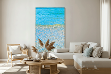 Living room with a large abstract painting of turquoise waters, a sofa, plants, and a coffee table.