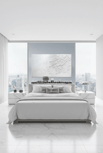 Modern bedroom with white bed, cityscape view, and white minimalist abstract painting with 3d textures, by artist Julia Apostolova.