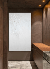 Abstract white painting with rough texture on a white wall in a modern hallway with marble floor and decorative lighting