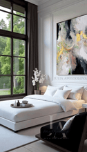 Modern bedroom with white bedding, large abstract art, and large window with greenery view.