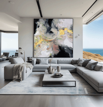 Modern living room with a large abstract painting on the wall with black, glod leaf and sage green colors. The room featuring a coastal view.