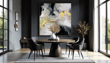 Modern dining room with a round table and chairs, large gold leaf abstract painting on the wall, and large windows with greenery view.