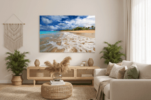 Living room with a large beach scene painting on the wall, plants, and a sofa.