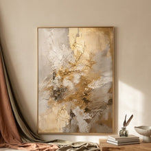 An abstract gold and white painting, displayed in a gold frame on a white wall 
