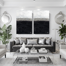 Modern living room with large black white silver leaf wall art, a gray sofa, glass coffee table, and decorative elements.