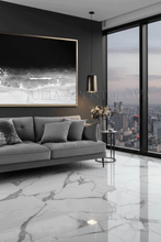 Modern living room with gray sofa, marble floor, cityscape view, and a large framed black white ocean wall art, by artist Julia Apostolova