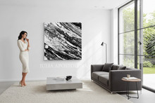 Woman standing in a modern living room with a large abstract black and white painting on the wall.