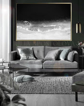 Living room with a gray sofa, decorative pillows, and a framed black and a black white minimalist ocean artwork on the wall.