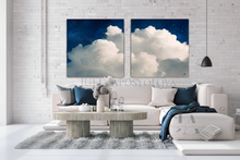 Living room with a white sofa, coffee table, and two large cloud-themed wall art pieces.
