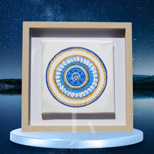 A framed circular mandala artwork with intricate patterns and blue, gold, white colors , surrounded of blue sky with stars, and a lake as background. Ideal art gift for Christmas, birthday, and any occasion.
