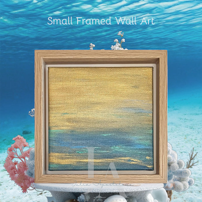 A small framed painting depicting an underwater scene with a coral reef, fish, and a wooden frame floating in the water