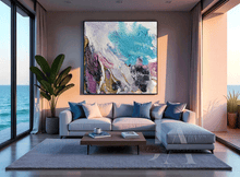 Modern living room with a large abstract painting, gray sofa, and coffee table by a large window with ocean view.