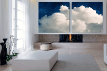 Two framed artworks of clouds above a fireplace in a modern living room.