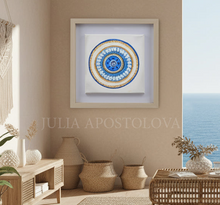 Framed artwork with a circular design in a living room setting, featuring ocean view.