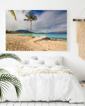 Beach scene with palm tree and white fence on a wall above a bed.