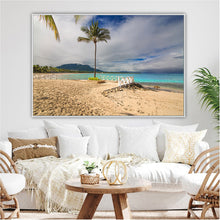 Beach scene framed as wall art in a living room with a sofa and decor.