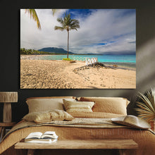 Beach scene with palm tree and turquoise water on a wall above a brown sofa.