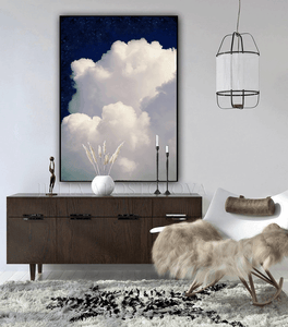 Large white cloud against a navy blue celestial sky painting , hanging over dark 
wooden cadenza , in modern minimalist boho living room setting. 