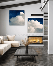 Modern living room with a fireplace, sofa, and two cloud-themed artworks.