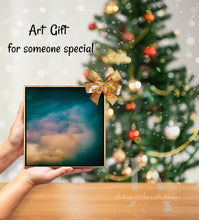 Framed artwork with a gold bow held in front of a decorated Christmas tree.