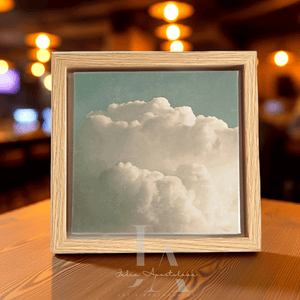 Framed photograph of a cloud on a wooden surface with blurred lights in the background